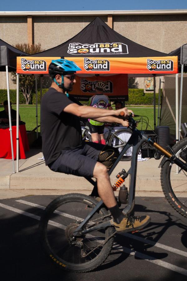 A bicyclist performing a wheelie in front of The SoCal Sound booth at CSUN Bikefest.