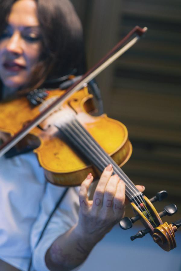 close shot of amanda shires playing violin with left hand tattoo and bow on strings